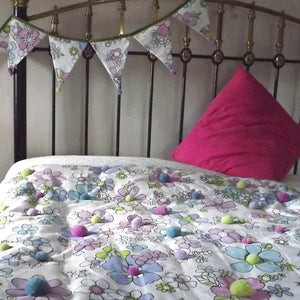 Matching Quilted Bed Throw and Bunting.  To make your own unique bed throw use flowery fabric and tie quilt in the flower's centres with pompoms. Make some matching bunting to enhance it.