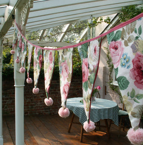 Decorate your outside space for a summer party with customised pompom bunting. Pretty rosy fabric was chosen, with a small pink pompom attached to each flag. 12 pompoms this size can be made at a time on a Multipom