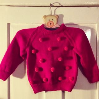 Add pompoms to a childs jumper to make it extra special. Thread and pass the ties through the jumper and knot on the back.